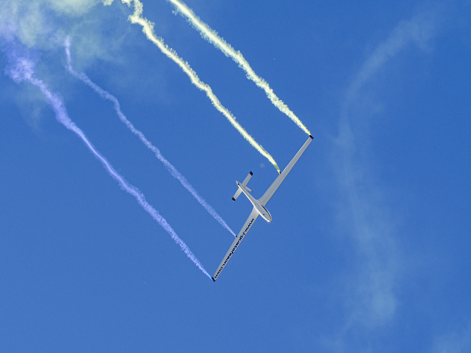 Ett stort vitt flygplan l&auml;mnar fyra streck efter sig p&aring; den bl&aring; himlen.