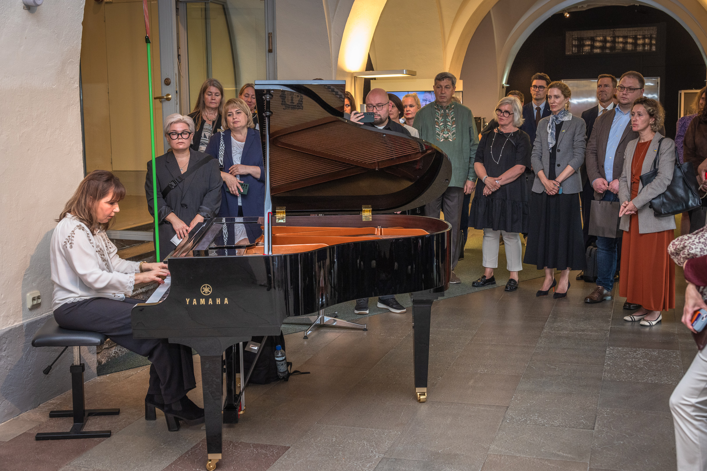 En pianist spelar p&aring; flygel f&ouml;r en samling m&auml;nniskor.
